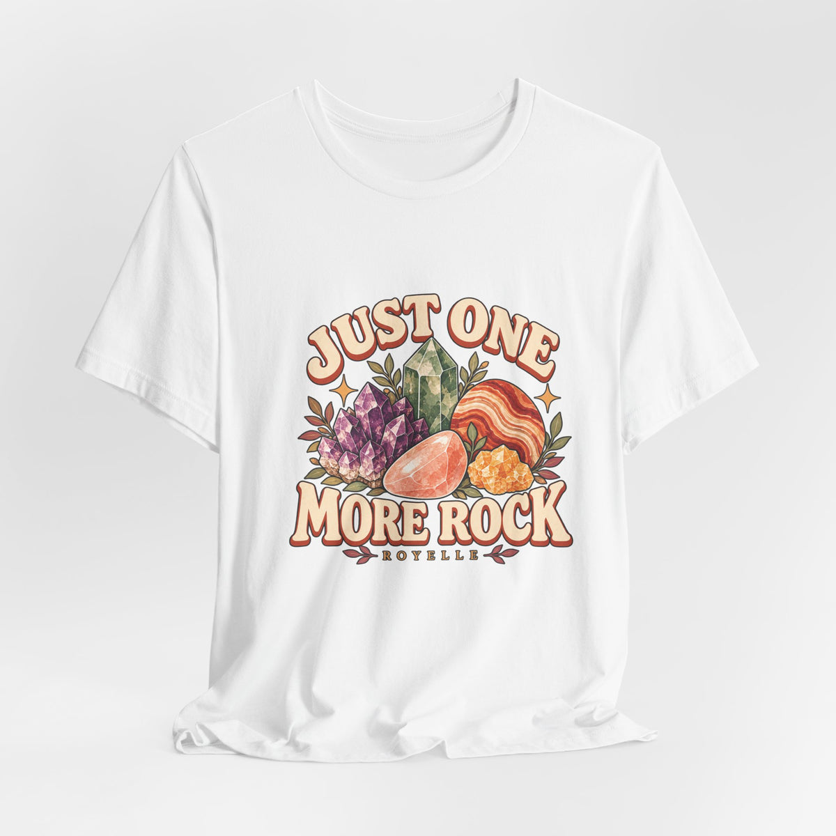 Royelle Just One More Rock T-shirt in White, hanging front view, with colorful illustrated minerals and slogan.