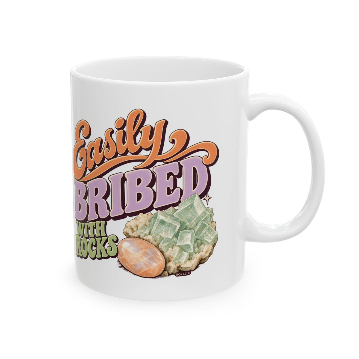 White Easily Bribed with Rocks ceramic mug with retro orange and purple lettering, green crystal artwork and an orange stone — handle-left view.